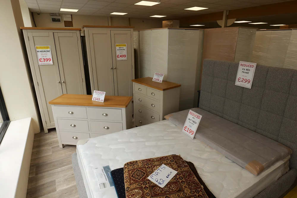 A bed displayed alongside wardrobes, a chest of drawers and bedside furniture