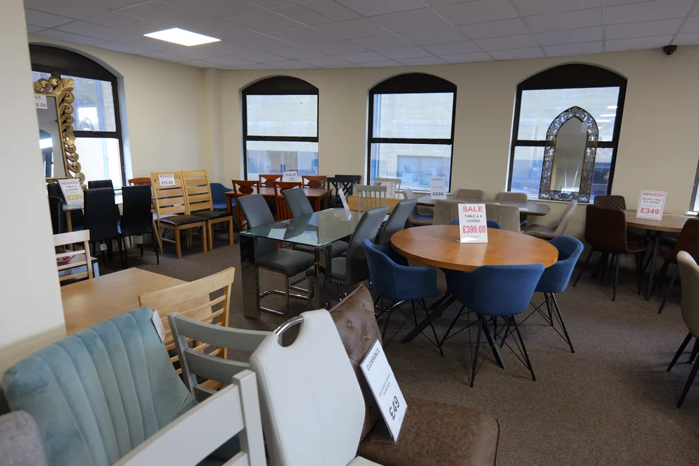 Dining tables and upholstered dining chairs arranged in the furniture showroom