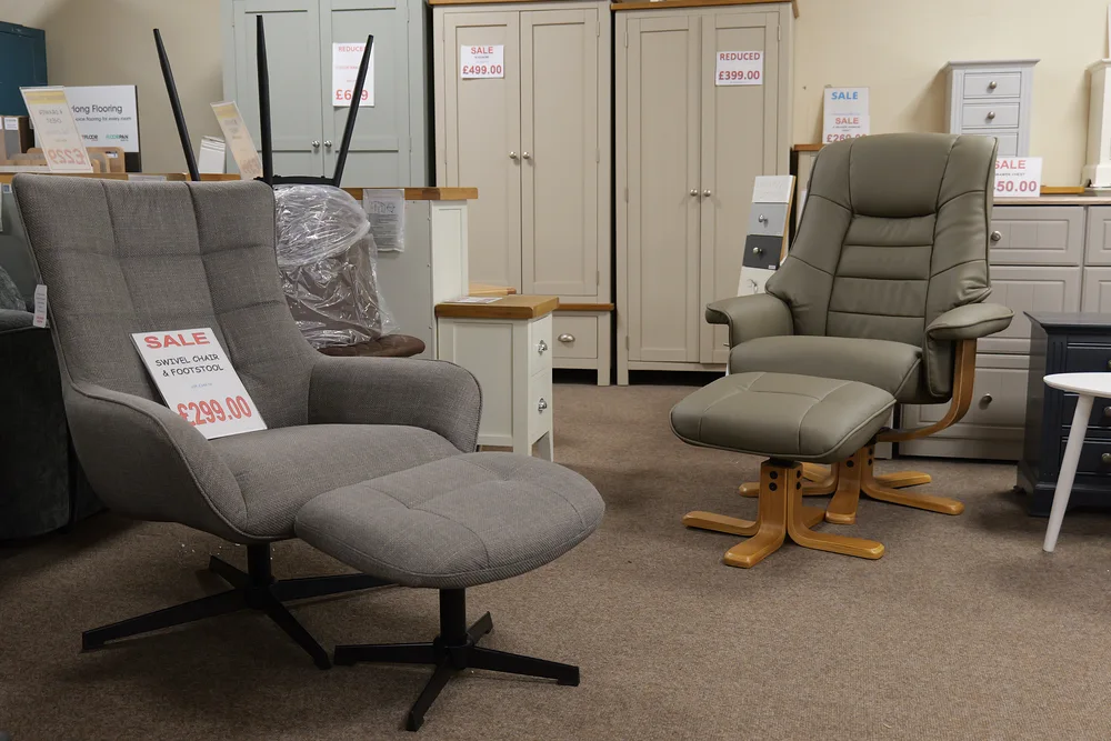 Two recliner chairs with matching footstools displayed in front of bedroom furniture