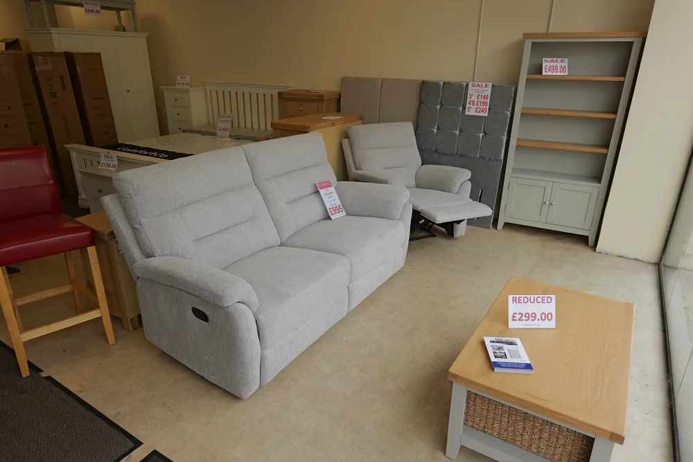 A pale upholstered sofa and matching chair with other furniture in the showroom